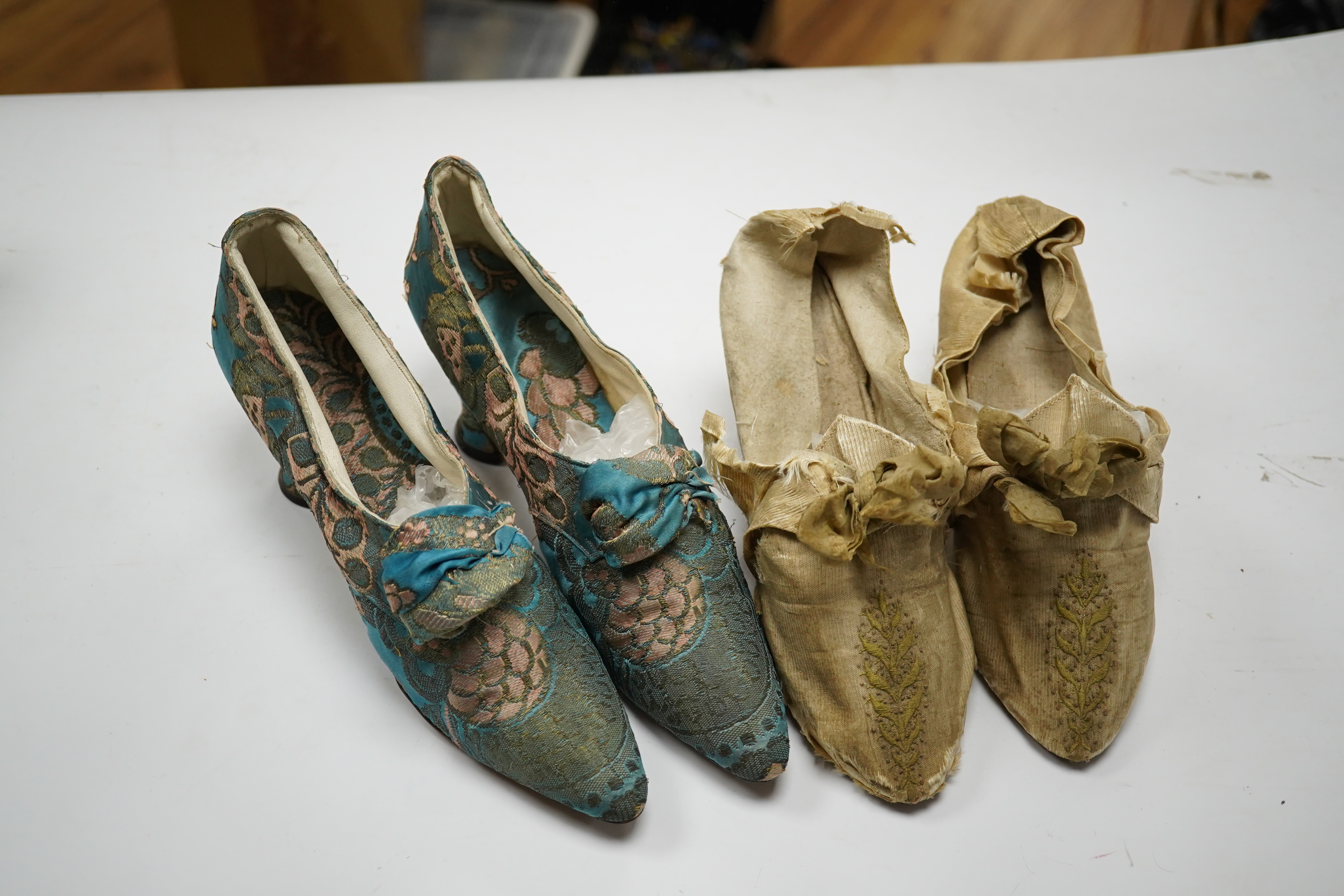 A pair of 18th century cream silk and embroidered ladies shoes together with a later 19th century silk brocade pair of ladies shoes, retailed by C. Moycopf, Burlington Arcade, both pairs lined in soft cream kid leather.